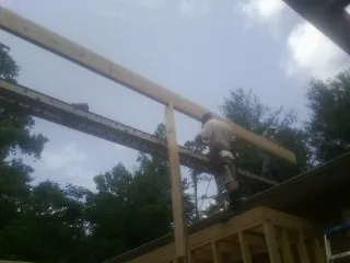 Carpenter setting a ridge beam over a new addition frame — Ice Dam Removal by Roofing Brothers in Enderlin