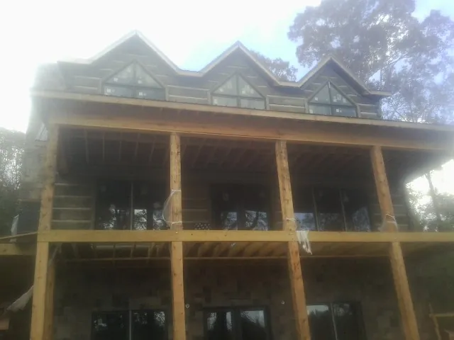 Dormers and porch framing on a large log home under construction — Roof Coating work by our crew in Enderlin