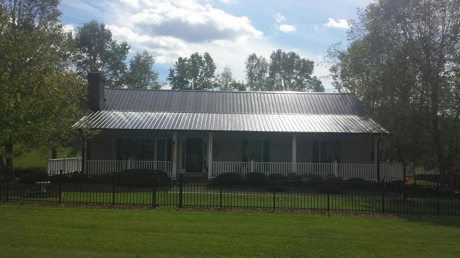 Gray metal roof on a brick ranch with a full width front porch — Gutter Guard Installation work by our crew in Enderlin