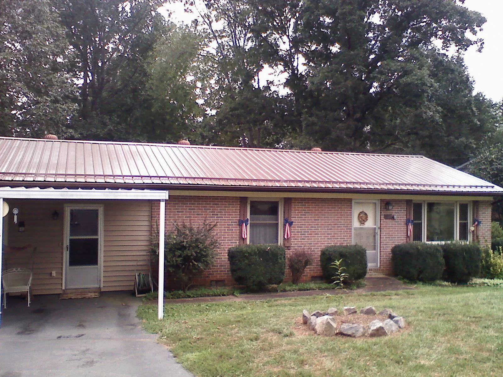 Bronze metal roof and carport on a brick ranch home — Roof Repair work by our crew in Enderlin