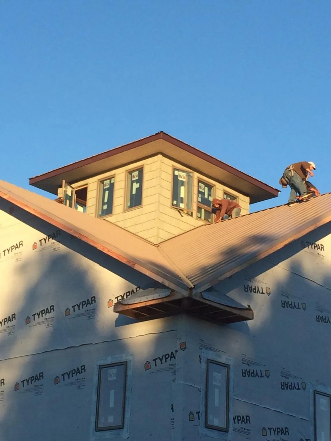 Roofers working around a rooftop cupola on a new metal roof at sunset — Roof Waterproofing in Enderlin by Roofing Brothers